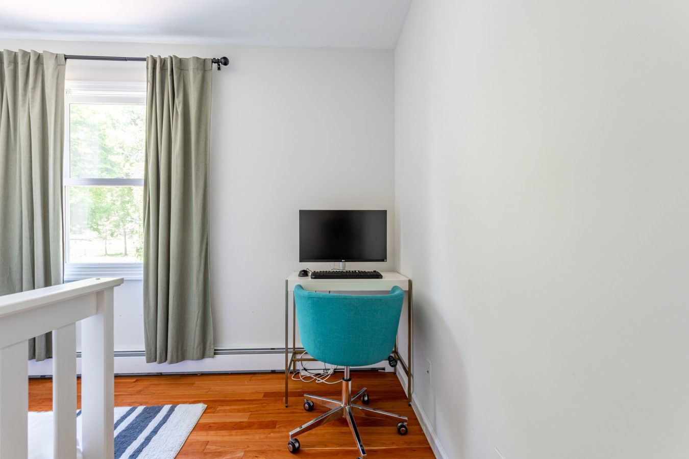 A room with a desk, a chair, a TV, and a window with curtains.