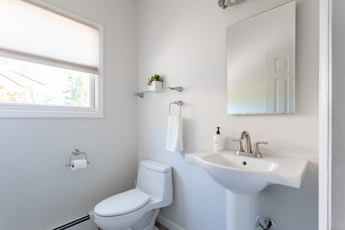 Een moderne badkamer met toilet, wastafel en spiegel.