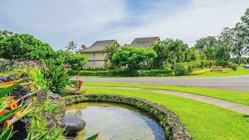 A residential area with a pond, lush greenery, and houses with sloped roofs.