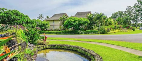 A residential area with a pond, lush greenery, and houses with sloped roofs.