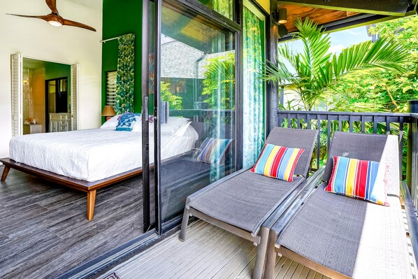 Ein Zimmer mit einem Bett, einer Couch und einem Balkon mit Blick auf Grünflächen.