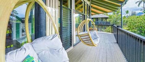 A wooden deck with a hanging chair and a cushioned seating area.