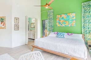 Ein Schlafzimmer mit einem Bett, einem Deckenventilator, einer grünen Wand und einem Gemälde.