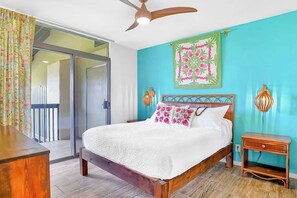 Ein Schlafzimmer mit Bett, Deckenventilator, Wandkunstwerk und Nachttisch.