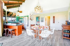 A modern kitchen with a central island, white chairs, and a dining table set for four. - NEW Fall Deal A Sunlit Princeville Great Room Near Hanalei and Anini (Princeville)