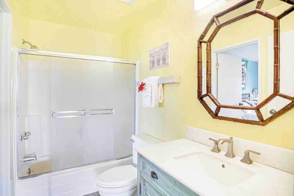 A bathroom with a glass shower enclosure, a toilet, a sink with a mirror, and a towel rack.