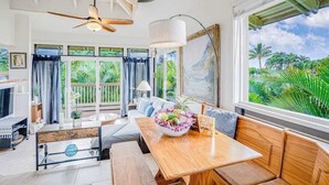 A spacious room with a wooden dining table, a sofa, and a ceiling fan. - NEW Corner Princeville Loft Studio with Hanalei Mountain Views (Princeville)