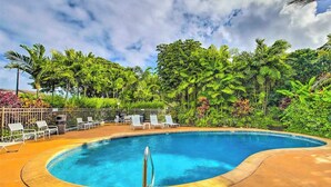A swimming pool with lounge chairs, surrounded by lush greenery and palm trees. - *New* Ground-Floor Kauaʻi Oceanfront Studio, Steps to Beach (Kapaa)