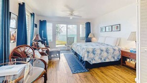 A bedroom with a bed, a desk, a chair, a ceiling fan, and a view of the outdoors. - *New* Ground-Floor Kauaʻi Oceanfront Studio, Steps to Beach (Kapaa)
