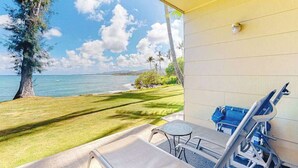 A balcony with a view of the ocean, a lawn, and a blue chair. - *New* Ground-Floor Kauaʻi Oceanfront Studio, Steps to Beach (Kapaa)