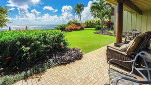 A patio with outdoor furniture, a view of the ocean, and a well-maintained garden. - *NEW* Oceanfront Wailua Days at Lanikai, Steps from Lae Nani (Kapaa)