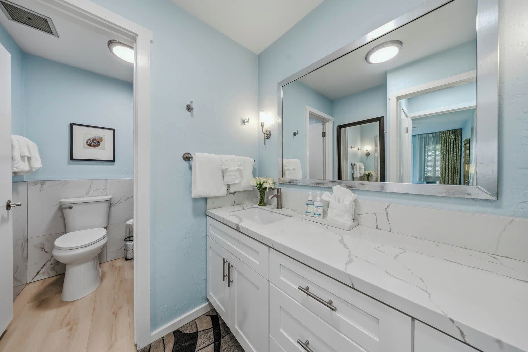A bathroom with a toilet, a sink, a mirror, and a shower area.