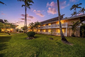 A two-story hotel with a balcony on the second floor, surrounded by palm trees and a well-maintained lawn. - *NEW* Fall $pecial Beachside Kapaa Condo with Three Pools and Hot Tubs (Kapaa)