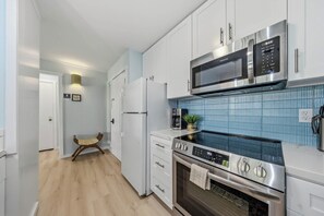 A modern kitchen with stainless steel appliances, a microwave, and a tiled backsplash. - *NEW* Fall $pecial Beachside Kapaa Condo with Three Pools and Hot Tubs (Kapaa)