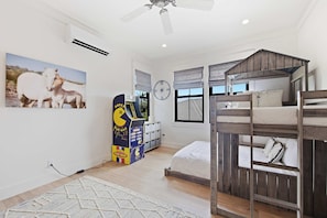 A room with a bunk bed, a Pac-Man arcade machine, a clock, and a painting of horses. - Custom Poipu Home on Kiahuna Golf w/ Poipu Beach Athletic Club Pool & Courts (Koloa)