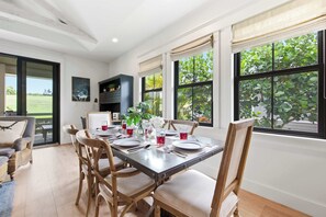 A dining area with a table set for four, surrounded by wooden chairs, with a view of greenery outside. - Custom Poipu Home on Kiahuna Golf w/ Poipu Beach Athletic Club Pool & Courts (Koloa)