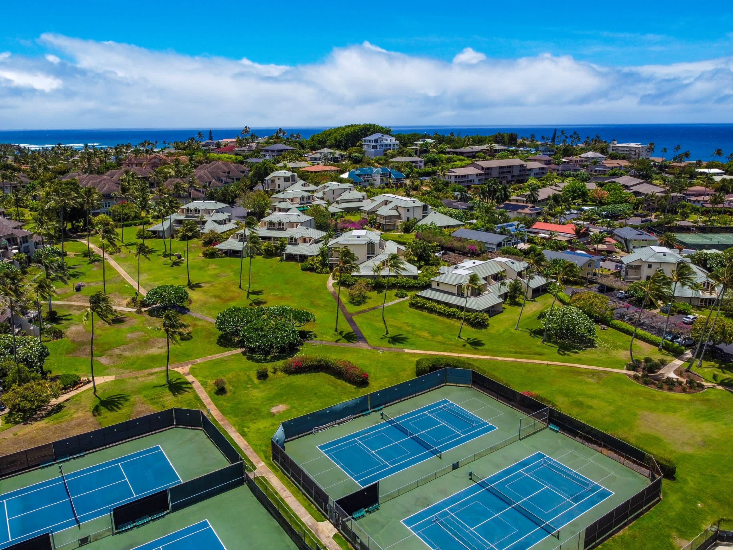 Um bairro residencial com várias casas, quadra de tênis e vista para o oceano.