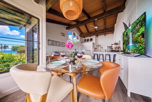 A dining area with a glass table, orange chairs, and a view of the ocean. - Hanalei Bay Mauna Kai 5- Pool, Kitchen, Beach Gear, WIFI, W/D, Family Friendly (Princeville)