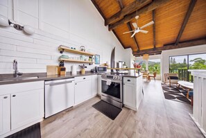 A modern kitchen with white cabinetry, a wooden ceiling, and a view of the outdoors. - Hanalei Bay Mauna Kai 5- Pool, Kitchen, Beach Gear, WIFI, W/D, Family Friendly (Princeville)