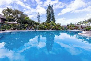 A clear blue pool surrounded by lounge chairs and umbrellas, with tropical plants and a clear sky in the background. - Hanalei Bay Mauna Kai 5- Pool, Kitchen, Beach Gear, WIFI, W/D, Family Friendly (Princeville)
