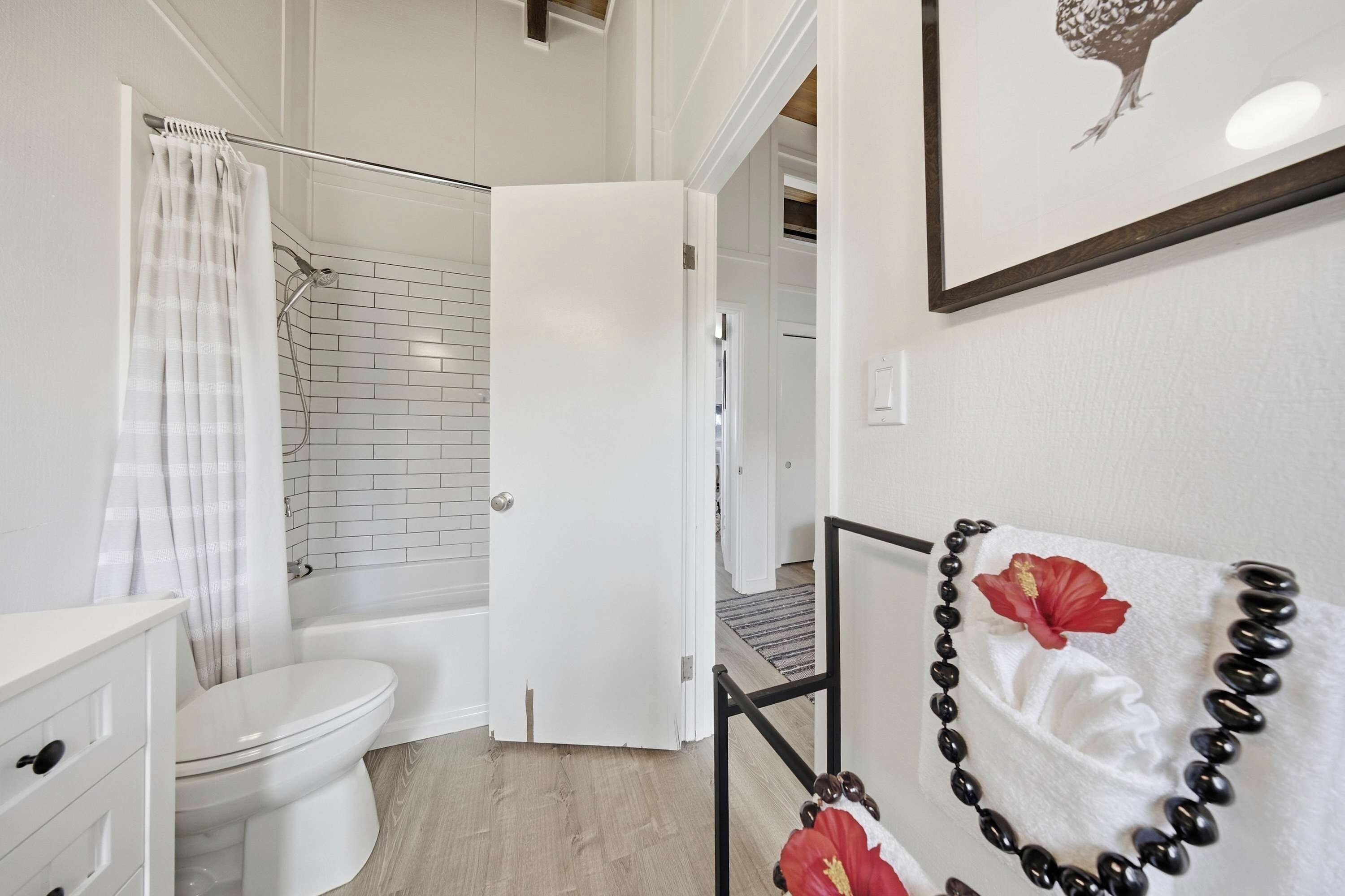 A bathroom with a toilet, shower, and a towel rack with a decorative item.