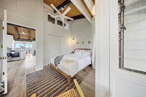A spacious bedroom with a large bed, a wooden ceiling, and a view of the kitchen. - Hanalei Bay Mauna Kai 5- Pool, Kitchen, Beach Gear, WIFI, W/D, Family Friendly (Princeville)
