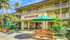 Un hôtel doté d’un balcon, d’une enseigne indiquant « Île sur la plage » et d’un banc en bois.