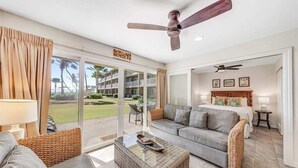 A hotel room with a balcony, a ceiling fan, a bed, a sofa, and a coffee table. - *New* Kapaa Family Retreat with Two Pools and Lanai (Kapaa)