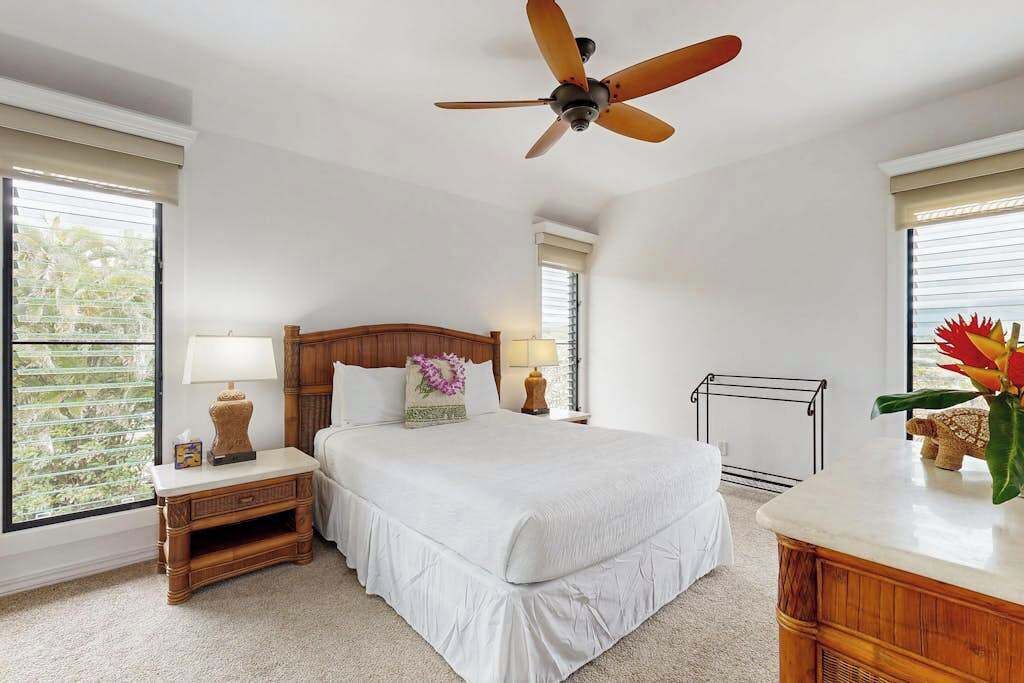 A bedroom with a bed, a nightstand, a dresser, a ceiling fan, and a window with blinds.