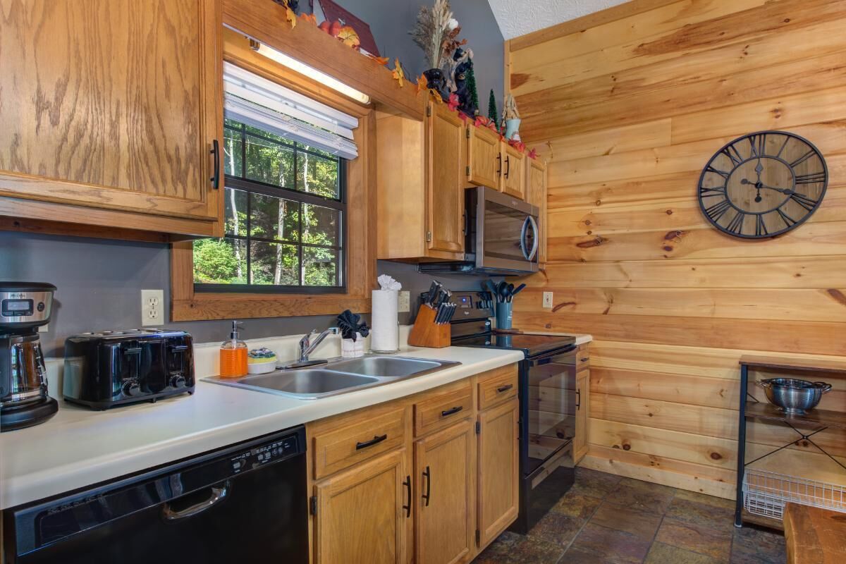 A kitchen with wooden cabinets, a microwave, a sink, and a clock on the wall.