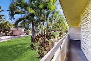 A balcony with a view of a well-maintained lawn and palm trees. - *New* Ground-Floor Kapaa 1BR Steps from the Beach (Kapaa)