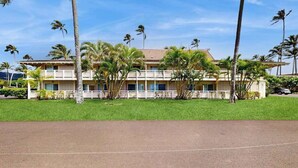 A two-story building with a flat roof, surrounded by palm trees and a well-maintained lawn. - *New* Ground-Floor Kapaa 1BR Steps from the Beach (Kapaa)