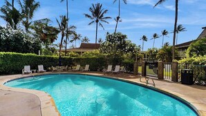 A swimming pool with lounge chairs, palm trees, and a gated area. - *New* Ground-Floor Kapaa 1BR Steps from the Beach (Kapaa)