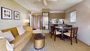 A living room with a sofa, a coffee table, a dining table with chairs, a ceiling fan, and framed pictures on the wall. - *New* Ground-Floor Kapaa 1BR Steps from the Beach (Kapaa)