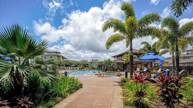 Um resort com piscina, palmeiras e espreguiçadeiras.