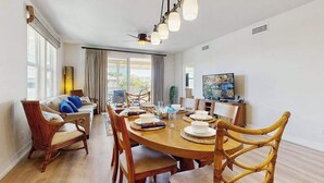Uma sala de jantar com uma mesa redonda, cadeiras e um ventilador de teto.