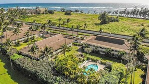 Vista aerea di un resort con piscina, spiaggia e palme.