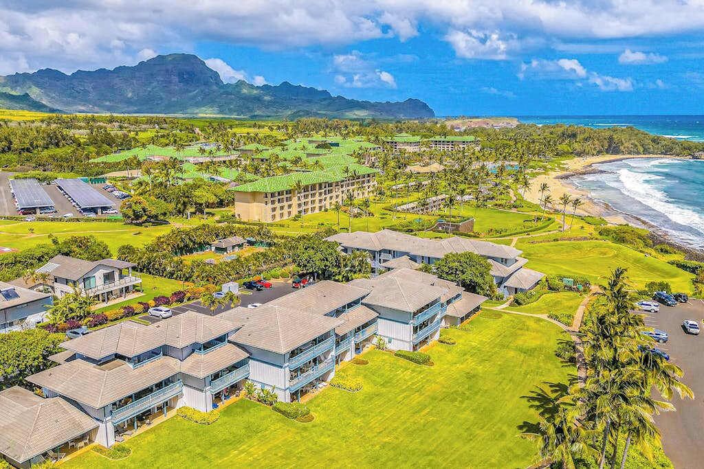 Un resort con varias edificaciones, un campo de golf y vistas a la playa.
