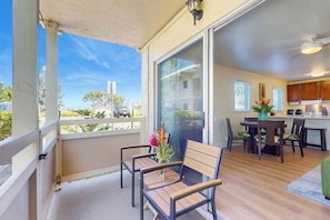 A balcony with a view of a residential area, a dining area with a table and chairs, and a kitchen with cabinets and a countertop. - Ground-Floor Kapaa Retreat 250 Yards from the Beach (Kapaa)
