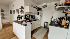 Een moderne keuken met witte kasten, een koffieapparaat en diverse keukengerei.
