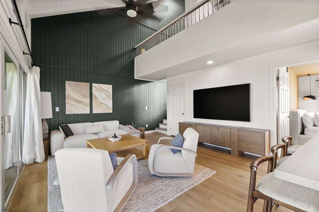 Una sala moderna con un sofá, sillas, una mesa de centro y un televisor.