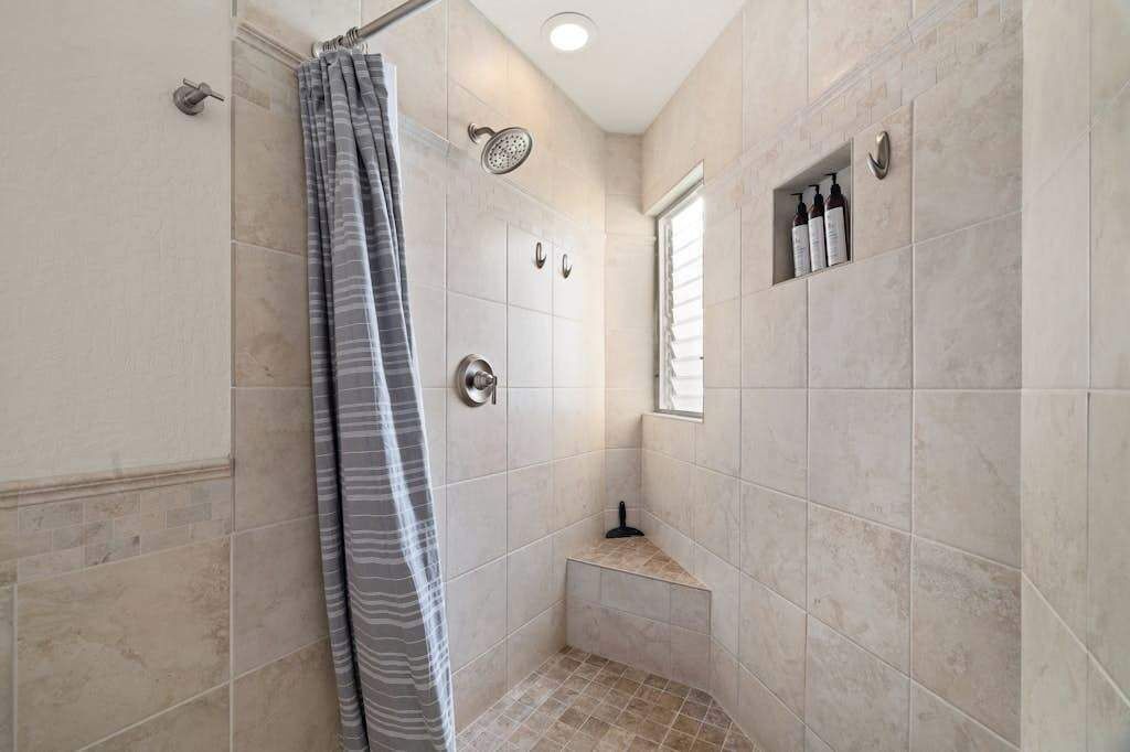 A shower with a showerhead, a towel rack, and a shelf with toiletries.