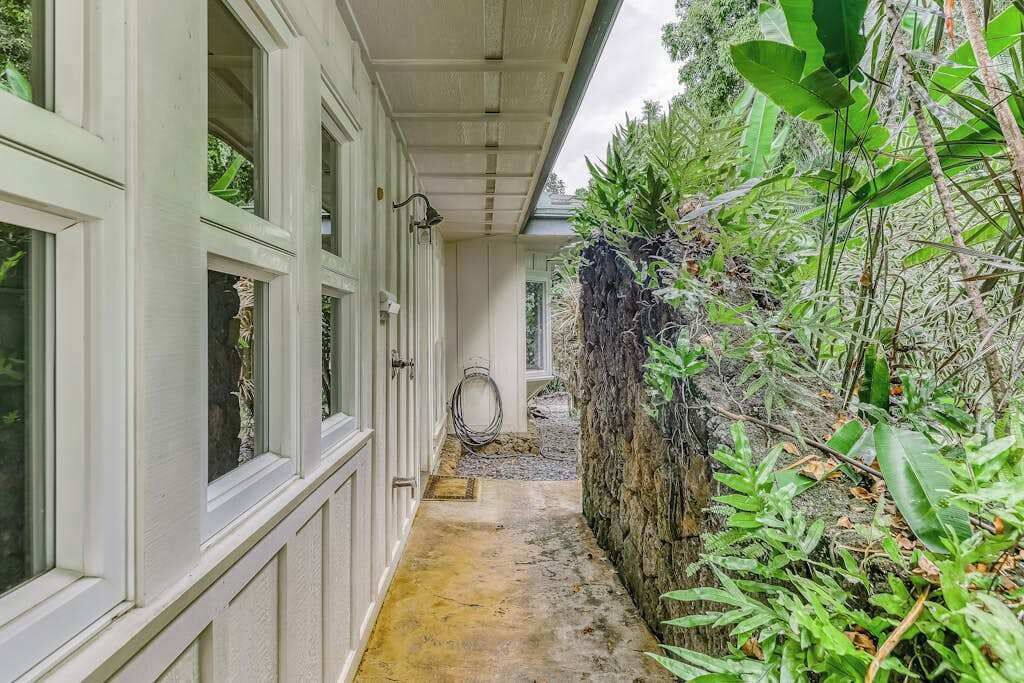 Un sendero estrecho que conduce a un edificio con múltiples ventanas y una pared de piedra a un lado.
