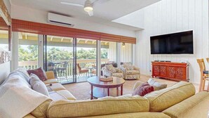 A spacious living room with a sofa set, a coffee table, and a flat-screen TV mounted on the wall. - *NEW* Air-Conditioned Poipu Retreat, 100 Yards from Brennecke's (Koloa)