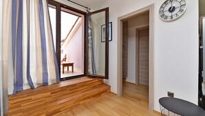 Ein Zimmer mit Holzboden, einer Schiebetür zum Außenbereich, einem schwarzen Stuhl und einer Wanduhr.