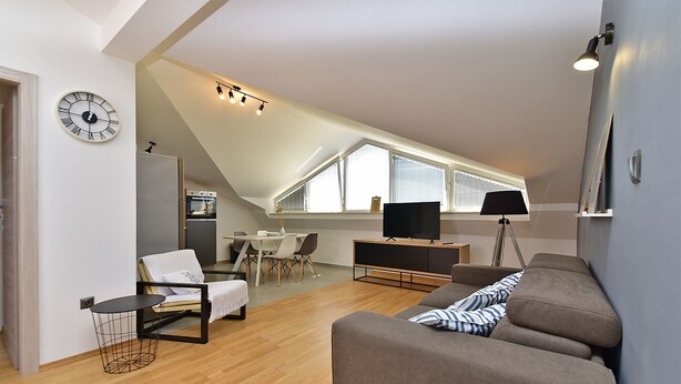 Eine moderne Loftswohnung mit Essbereich, einer Couch, einem Fernseher und einer Küche.