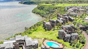 Un resort con edificios de piedra, piscina y vista al océano.