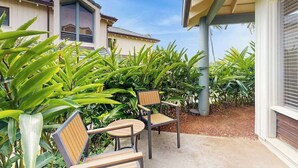Een overdekt buitengebied met een patio tafel en stoelen, omgeven door weelderige groene beplanting.