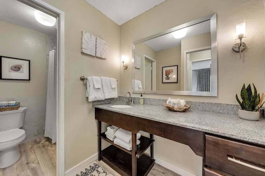 A bathroom with a sink, mirror, towel rack, and a potted plant.