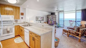 A modern kitchen with wooden cabinets, a white stove, and a large island. - *NEW* Beachfront Kapa'a Stay with Pool and Coastal Views (Kapaa)